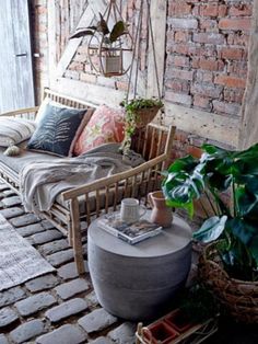 a living room with brick walls and stone flooring, potted plants in the corner