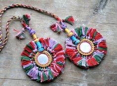 two colorful necklaces with tassels on a wooden surface