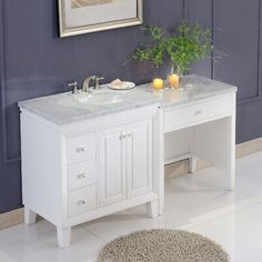 a white bathroom vanity with two sinks and a rug on the floor next to it