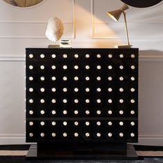 a black cabinet with lights on it in front of two wall clocks and a lamp