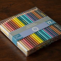 a box of colored pencils sitting on top of a wooden table