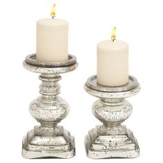 two white candles sitting on top of each other next to each other in metal holders