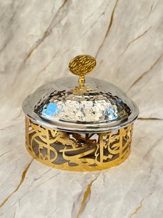 a silver and gold covered dish sitting on top of a marble counter