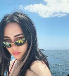 a woman wearing sunglasses standing on top of a boat