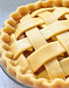 an apple pie with latticed crust in a glass pie dish on a counter top