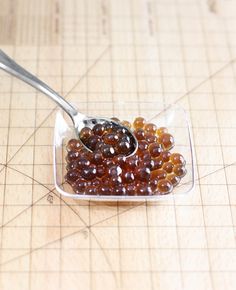 a spoon filled with jelly sitting on top of a cutting board