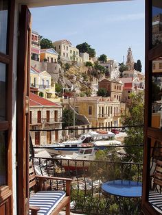 an open window looking out at boats docked in the water and buildings on the hillside