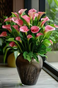 a vase filled with pink flowers sitting on top of a table next to a window