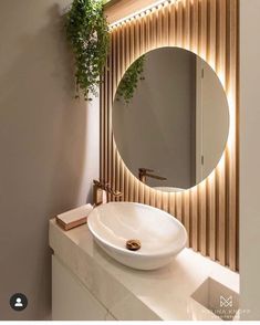 a white sink sitting under a round mirror