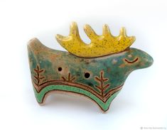 a ceramic brooch with a crown on it's head, against a white background