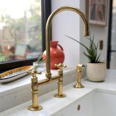 a kitchen sink with two faucets and a window in the backround