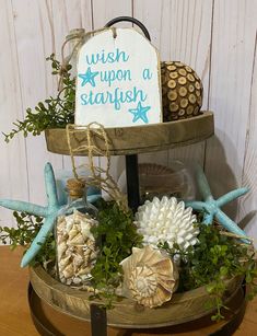 an arrangement of seashells and starfish in a wooden stand with a wish upon a starfish sign