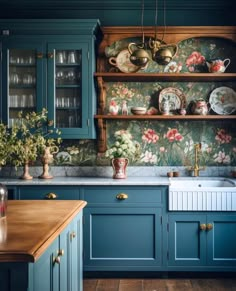 a kitchen with blue cabinets and floral wallpaper on the backsplash is pictured in this image