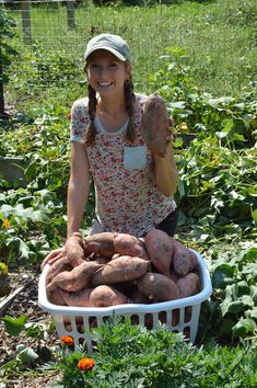 a woman is holding up some potatoes in her garden