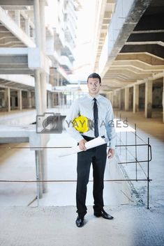 a man in a suit and tie holding a yellow hard hat with his hands on his hips