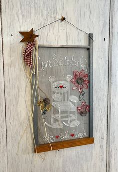 a glass sign hanging on the side of a white door with flowers and a bow