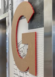 the letter c is made out of cardboard and placed in front of a metal refrigerator