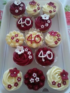 cupcakes decorated with red and white frosting are arranged in a square tray