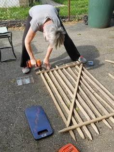 a woman is working on some kind of wooden flooring project with tools around her