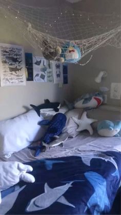 a bed with blue and white sheets, pillows and stuffed animals on the headboard