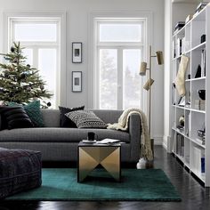 a living room filled with furniture and a christmas tree in the corner on top of a green rug