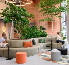 a woman sitting on a couch in the middle of a room with lots of plants