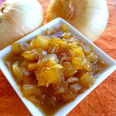 two onions are in a square bowl next to an onion and garlic dish on a table