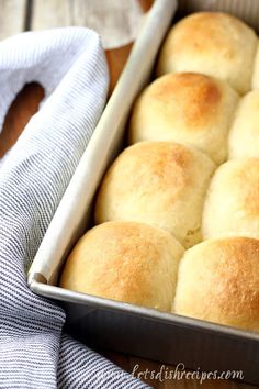 a pan filled with rolls sitting on top of a wooden table next to a blue towel