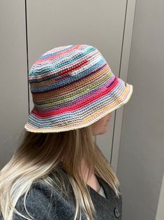 a woman wearing a multicolored hat standing in front of a wall