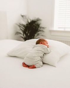 a baby sleeping on top of a white pillow