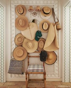 hats are hanging on the wall next to a wooden chair and hat rack in a room