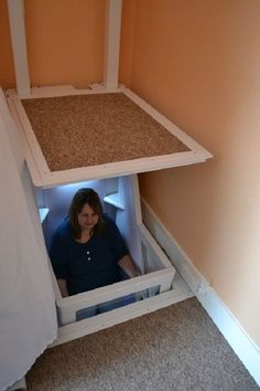 a woman is sitting in the bottom half of a cat house