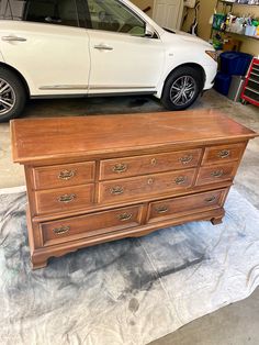 a white car parked next to a wooden dresser