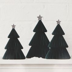 three small green christmas trees sitting on top of a white mantle