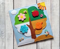 an apple tree with flowers, leaves and birds in it on a white wooden background