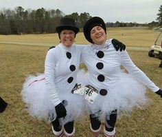 two women dressed up in costumes posing for a photo on the grass with their arms around each other