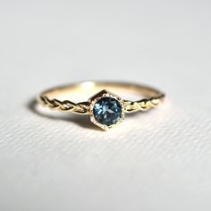 a gold ring with a blue stone in the center on a white surface, close up