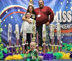 a man, woman and child posing for a photo in front of a trophy display