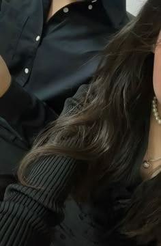 a close up of a woman with long dark hair and pearls on her necklaces