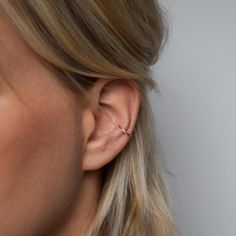 a close up of a woman's ear with a gold ring on the end