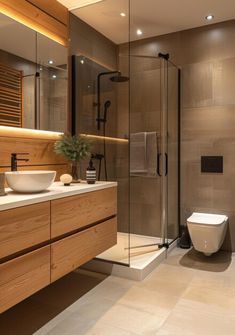 a bathroom with a sink, toilet and shower stall in the middle of it is illuminated by recessed lighting