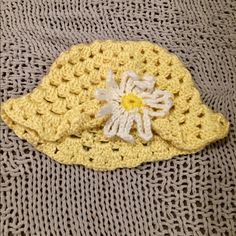 a yellow crocheted hat with a white flower on it