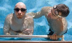 two men in swimming pool with one looking at the other man's eyeglasses