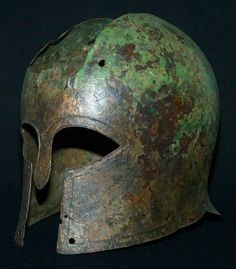 an old helmet that is worn and rusted with green paint on the inside, sitting on a black surface