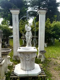 an old cemetery with statues and flowers in the foreground, surrounded by greenery