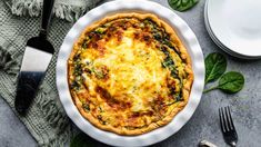 a quiche with spinach and cheese in a white pie dish on a table