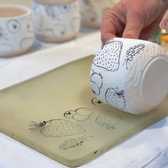 a person is pouring coffee into a cup on a tray with strawberries drawn on it