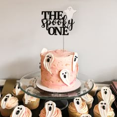 there is a cake and cupcakes on the table with ghost decorations around it