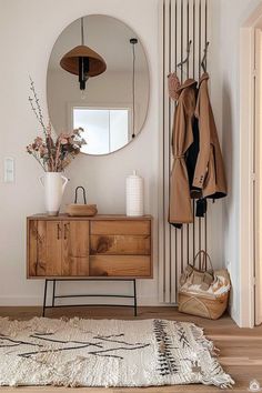 a room with a mirror, coat rack and rug on the floor in front of it