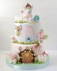 a three tiered cake decorated with fairy figurines